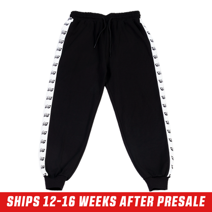 Black track pants with white side stripes featuring repeating killer whale silhouettes and a back pocket.