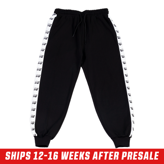 Black track pants with white side stripes featuring repeating killer whale silhouettes and a back pocket.