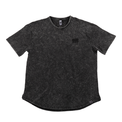 Close-up of black stonewash fabric with a gray tag featuring a black stylized "GS" logo near the hem.