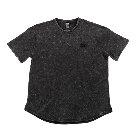 Close-up of black stonewash fabric with a gray tag featuring a black stylized "GS" logo near the hem.